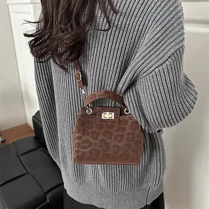 Close-up of leopard print mini crossbody bag with gold twist-lock and matte texture