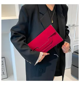 Detail of fuchsia suede envelope clutch with geometric layered flap design on a black blazer