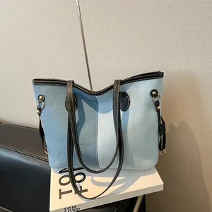 Large denim patchwork tote bag with black leather handles and white contrast stitching