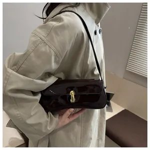 Detalle del bolso de hombro en charol marrón oscuro con hebilla dorada vintage en U
