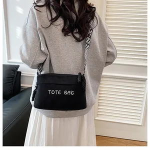 Detalle de bolso tote de pana negra con correa geométrica ancha y bordado TOTE BAG