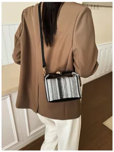 Detailed look at the black and white woven crossbody bag with golden metal twist lock
