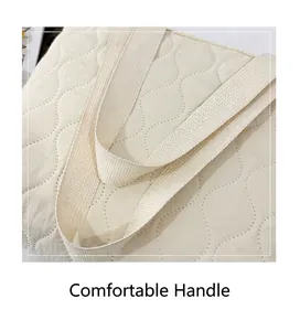 Close-up of comfortable wide webbing handles on a cream quilted space cotton handbag