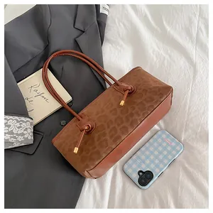 Detail of leopard print tote bag with brown leather straps and gold spherical accents