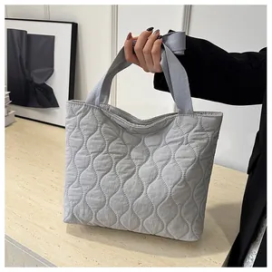 Detailed view of light gray quilted puffer tote bag featuring soft wave stitching pattern
