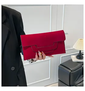Close-up of deep red matte envelope clutch bag with geometric flap and suede texture
