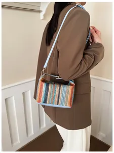Detail of colorful striped straw handbag with light blue strap and gold buckle hardware