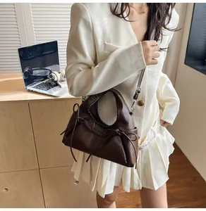 Detail of dark brown tote bag with bow tie design and ruched edges on soft leather