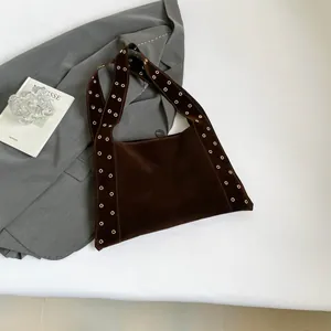 Détail macro du cabas en daim marron foncé avec œillets dorés et large bandoulière