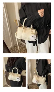 Detail der cremefarbenen Boston Bag mit Faltentextur, Goldbeschlägen und Plüsch-Anhänger