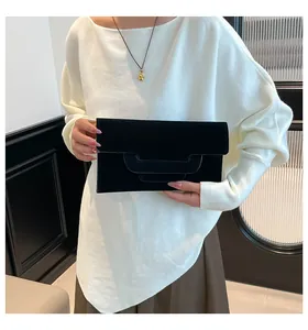 Detail of a black suede envelope clutch with layered U-shaped flap and minimalist texture