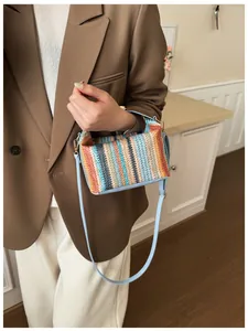 Detail of multi-color woven straw crossbody bag with light blue leather strap and gold hooks