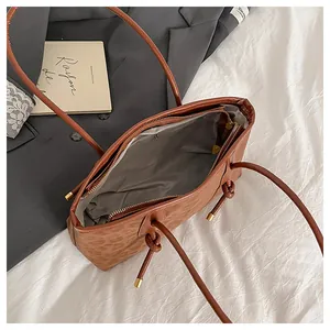 Detail view of the brown tote bag interior with grey lining and a golden zipper pocket