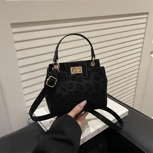 Detail of black leopard print crossbody bag with gold twist lock on a minimalist setup