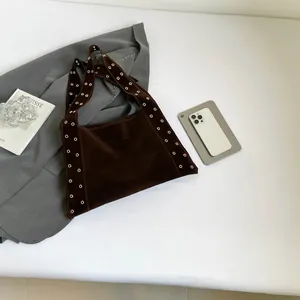 Détail du sac cabas en daim marron foncé avec œillets métalliques sur la bandoulière