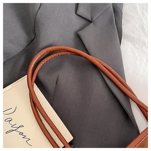 Close-up of brown leather shoulder straps with fine stitching on an office tote bag