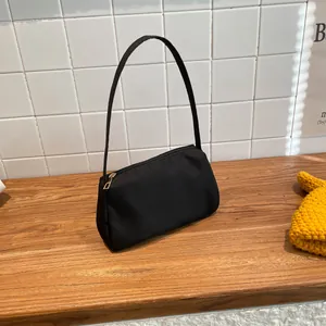 Close-up of minimalist black fabric underarm bag with gold zipper detail and smooth texture