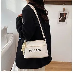Detail of off-white corduroy tote bag with black embroidery and woven shoulder strap