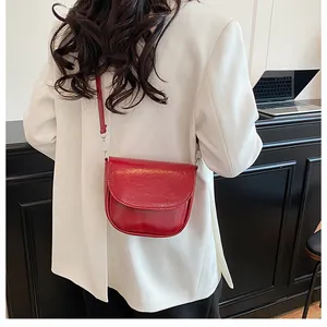 Vibrant red saddle bag in glossy leather worn by a model against a minimalist background