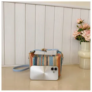 Detail of multi-color striped straw bag with light blue leather strap and metal clasp