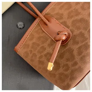 Detail of brown leopard print tote showing suede texture, leather knot, and gold metal tip