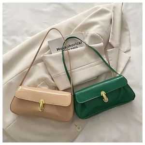 Detalle de bolso en charol brillante con hebilla de metal dorado y correa delgada
