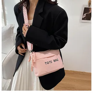 Close-up of pink corduroy tote bag with woven strap worn with a black blazer