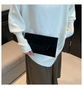 Detail of black envelope clutch featuring a layered fold design and premium matte texture