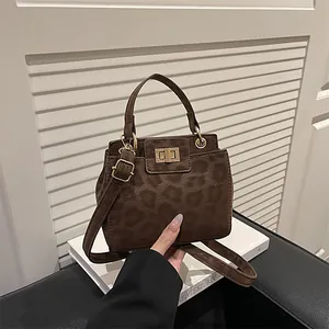 Detailed view of leopard print crossbody bag with gold twist lock and suede texture