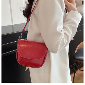 Detail of red faux leather saddle bag on white blazer highlighting sleek texture and style