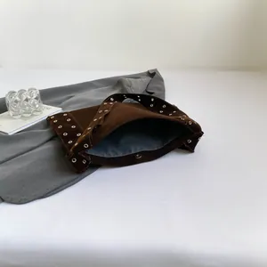 Détail du sac cabas en daim marron avec œillets dorés et fermeture magnétique