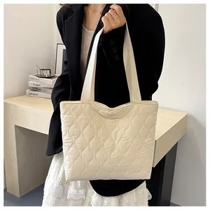 Close-up of wavy quilted pattern on a cream shoulder bag shown in an elegant interior setting