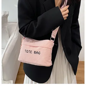 Detalle de bolso bandolera de pana rosa con correa ajustable ondulada sobre la modelo