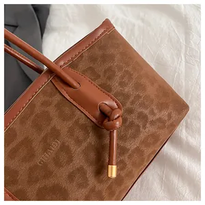 Detail of a brown leopard print tote bag featuring a knotted handle and logo embossing