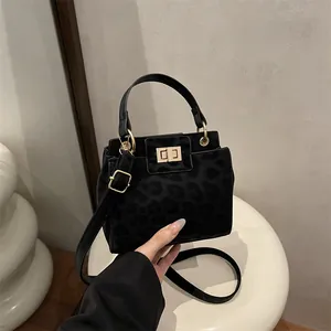 Detail of black leopard print crossbody bag with golden square lock and top handle