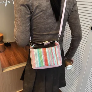 Colorful striped straw shoulder bag with pink leather strap shown on a model