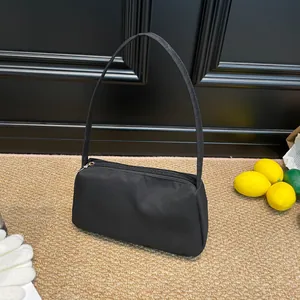 Minimalist black nylon shoulder bag with zipper closure on a stylish textured background