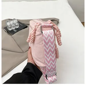 Detalle de textura de bolso bandolera de pana rosa con correa de tejido estampado
