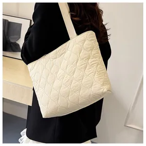 Close-up of wavy quilted tote bag in beige fabric with soft braided shoulder strap