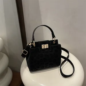 Detail of black leopard embossed shoulder bag with gold clasp and metal handle