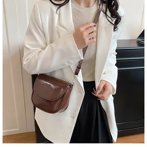Brown saddle bag in glossy patent leather styled with a white blazer for a chic look