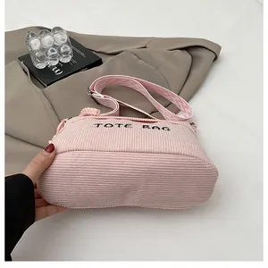 Detalle de bolso tote de pana rosa con bordado TOTE BAG y correa geométrica