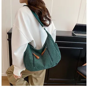 Detail view of dark green corduroy shoulder bag showing fabric texture and zippers