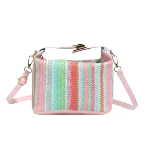 Rainbow striped woven crossbody straw bag with pink handles and gold hardware details