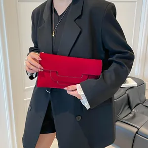 Elegant red suede envelope clutch bag held by a model in a formal black suit