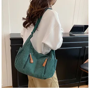 Detailed back view of a dark green corduroy crossbody bag worn by a model in a studio