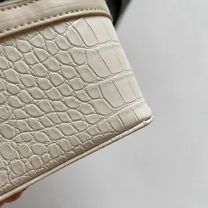 Primer plano de cuero beige con relieve de cocodrilo y costuras finas en el bolso