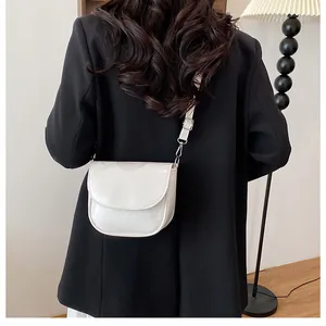 Detailed view of a white glossy saddle bag with silver metal hooks on a black blazer