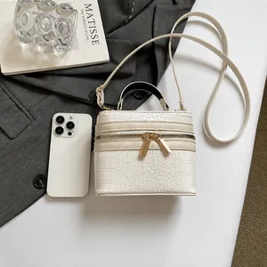 Bolso caja blanco efecto cocodrilo junto a un móvil para comparar el tamaño