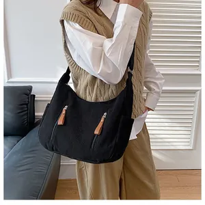 Detail of black corduroy hobo bag with front vertical zippers and brown leather pulls